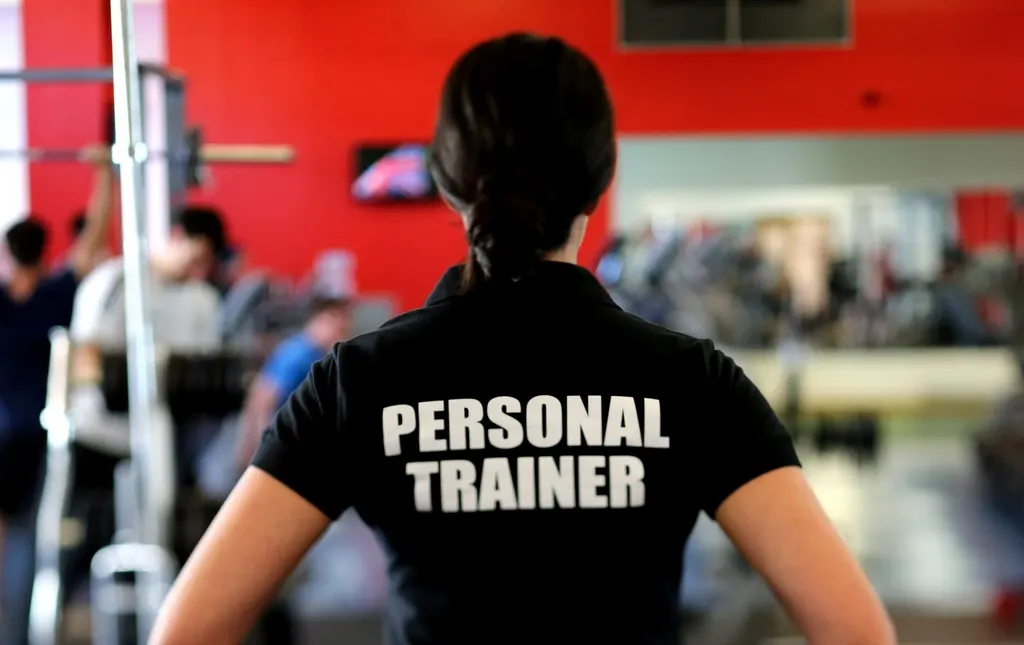 Personal trainer in a branded shirt standing in a gym